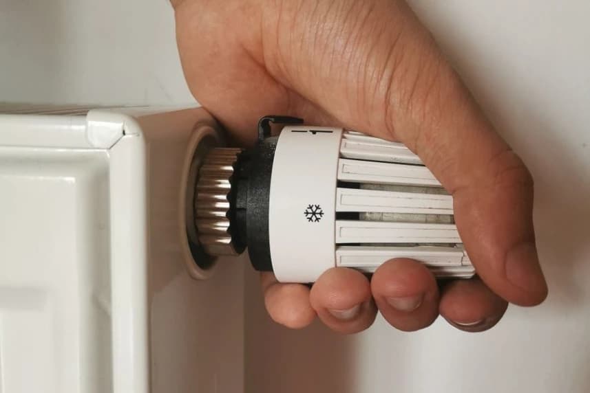 Bon Ciepłowniczy. Nowy rodzaj wsparcia. Komu przysługuje? Jak i gdzie złożyć wniosek? Dłoń na głowicy termostatycznej, która służy do regulowania temperatury w pomieszczeniu.