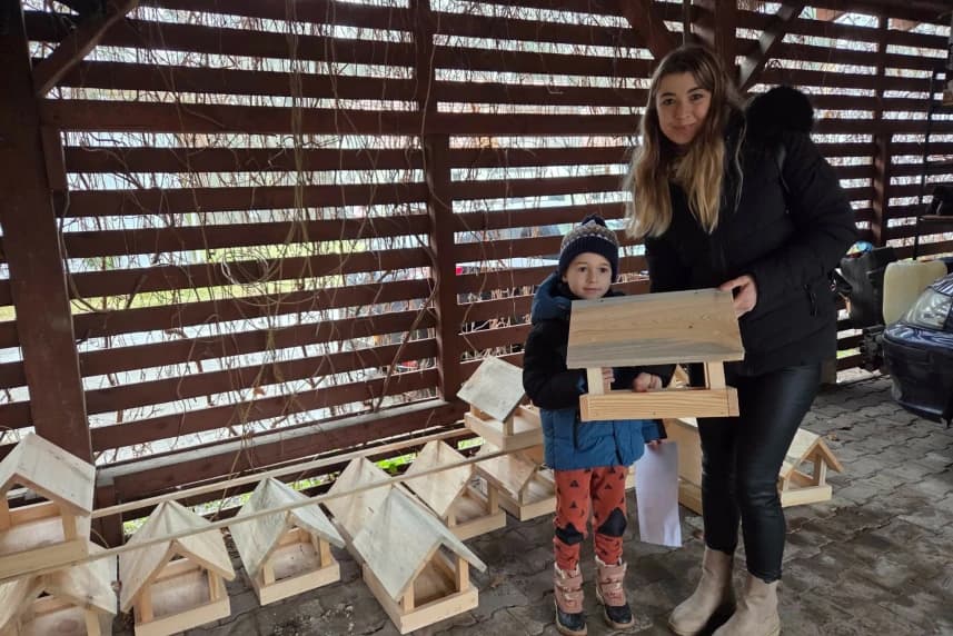 Lasy Miejskie: Karmniki rozdane! Młoda kobieta z dzieckiem odbiera karmnik dla ptaków.