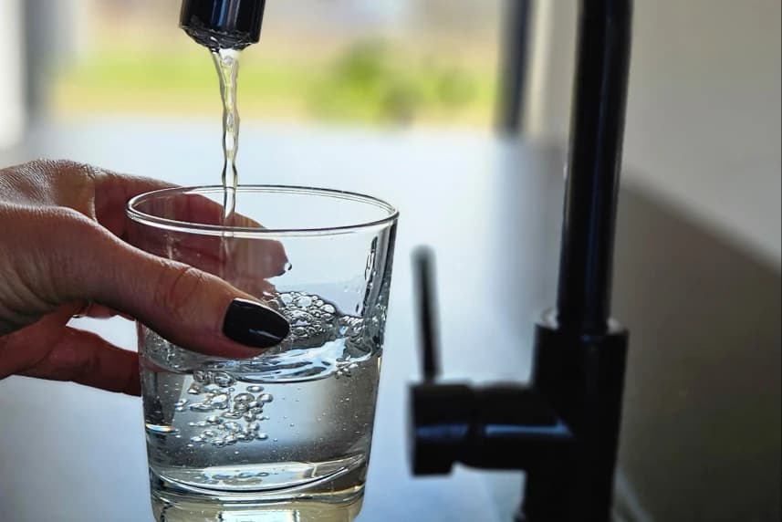 ZWiK: Uwaga na podróbki! Dłoń trzymająca szklankę napełniającą się wodą z kranu.