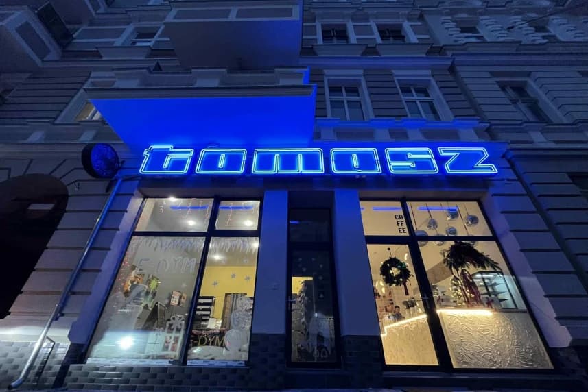 „TOMASZ” znowu świeci pełnym blaskiem Neon z napisem tomasz nad witryną sklepową