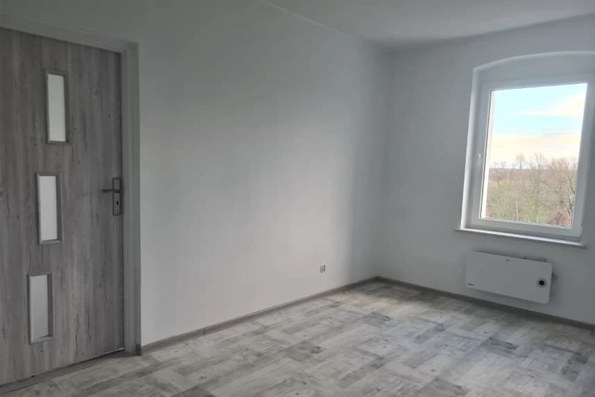 Najem lokali socjalnych. Wyniki naboru Pusty pokój z białymi ścianami, drzwiami i oknem.