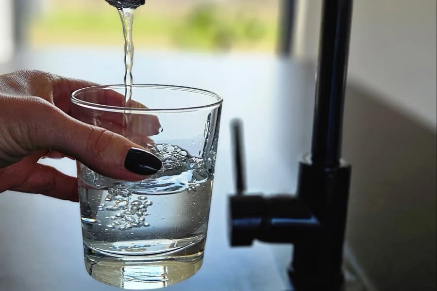 Woda znika na kilka minut i dzwoni całe miasto. Dlaczego 22 marca warto o niej mówić? Dłoń trzymająca napełniającą się szklankę wody.