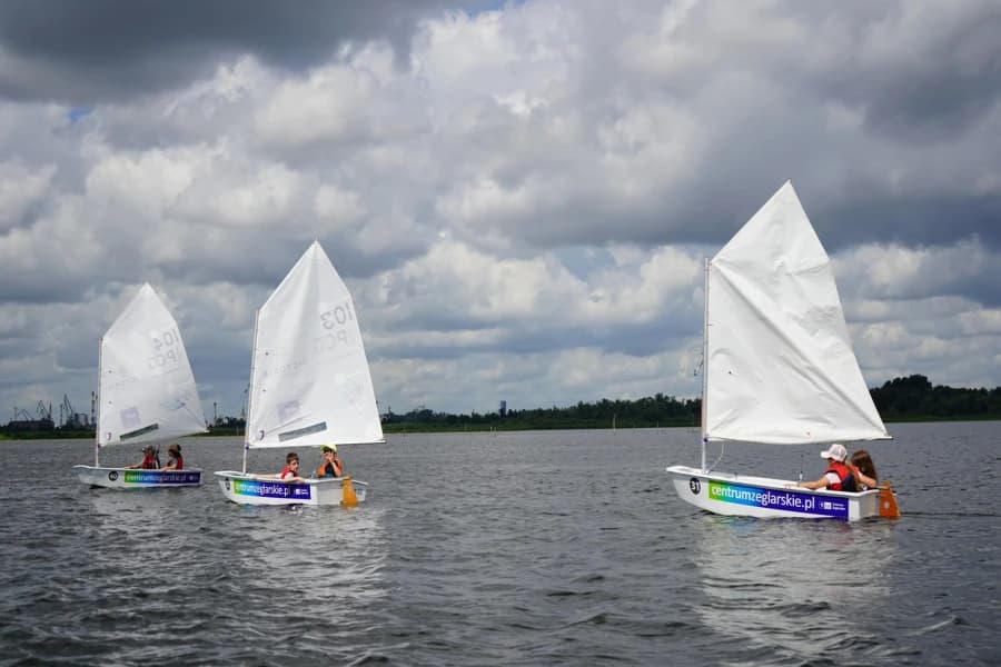 Startują zapisy na letnie półkolonie w Centrum Żeglarskim Trzy żaglówki na akwenie wodnym.