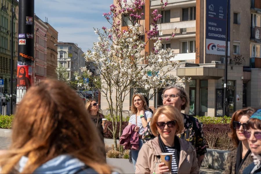 Już w tę niedzielę, zapraszamy na magnoliowy spacer! Grupa ludzi na tle magnolii