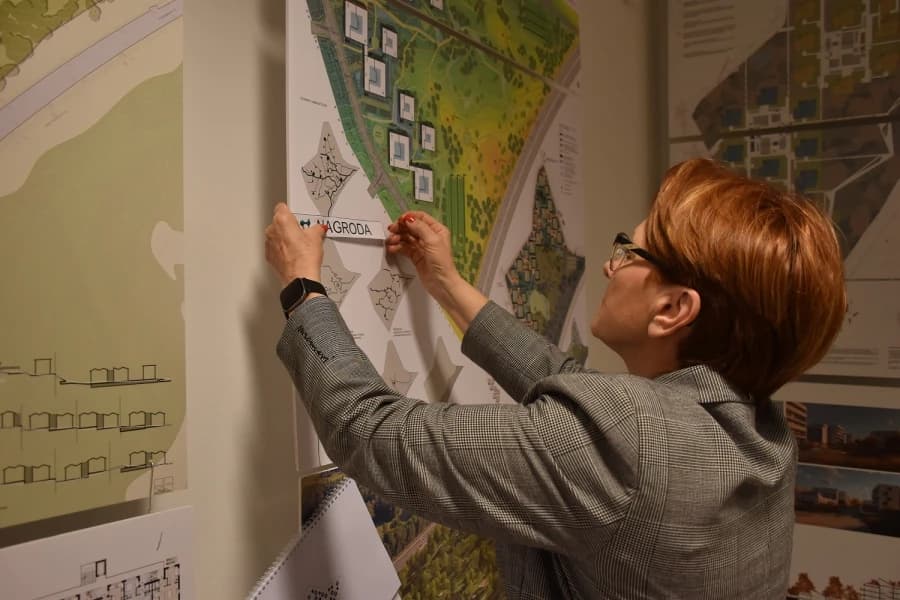 Szczecińskie TBS: Nowe osiedle w Podjuchach krok po kroku Kobieta stojąca przy tablicy informacyjnej.