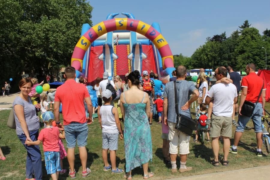Przed nami Wielki Piknik Pasji! Zapraszamy na Jasne Błonia Grupa ludzi stojąca przed dmuchanymi atrakcjami dla dzieci