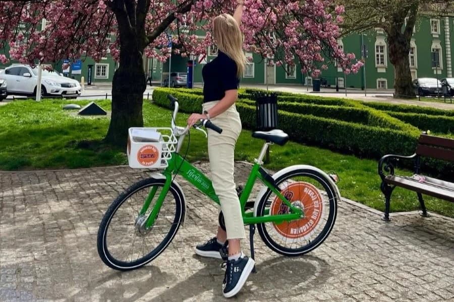 W sobotę rowerowa gra miejska z BikeS Kobieta w jasnych spodniach i ciemnej bluzce na zielonym rowerze.