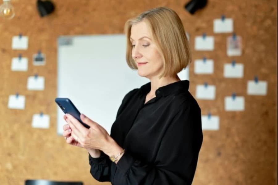 Ważna informacja dla użytkowników Mobilnej Karty Miejskiej Szczecin 1.0 Kobieta ubrana w czarną bluzkę trzyma w dłoniach telefon komórkowy.