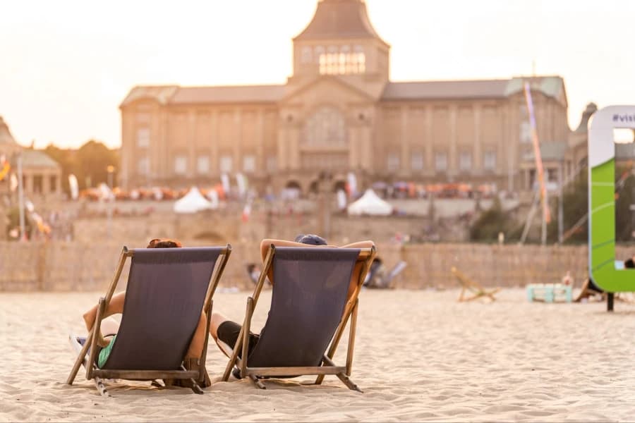 Wydarzenia w Szczecinie: 26-28 czerwca. Szykujemy się na gorący weekend w mieście Dwa leżaki plażowe. W tle duży budynek.