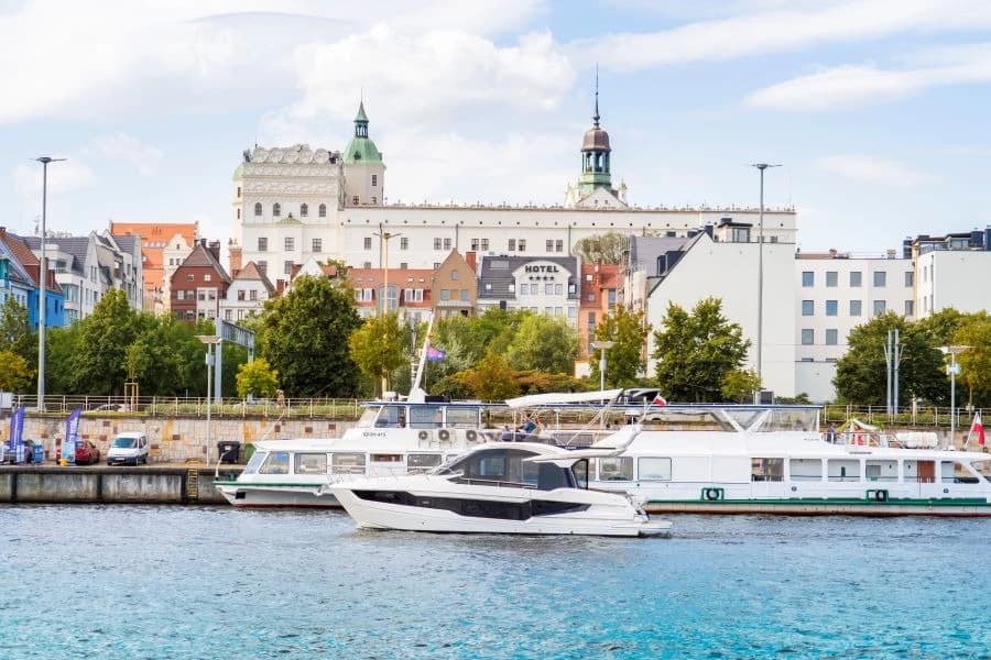 Łódź motorowa i statek białej floty na tle Zamku Książąt Pomorskich w Szczecinie.