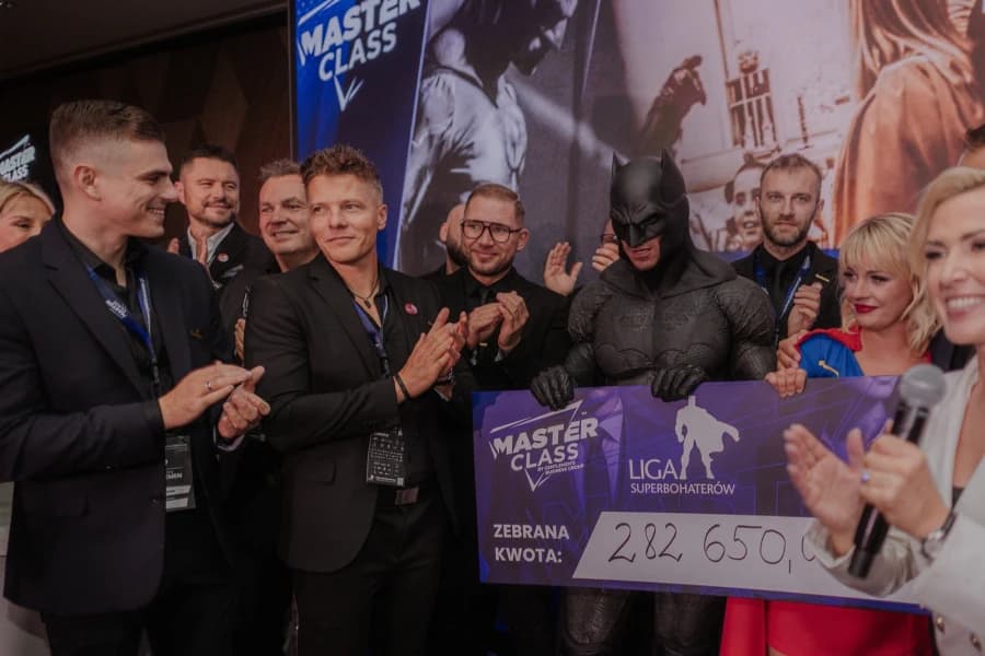 Master Class 2026 w Szczecinie. Jacek Walkiewicz i Kamil Kozieł na konferencji charytatywnej Grupa ludzi. W środku mężczyzna w stroju Batmana.