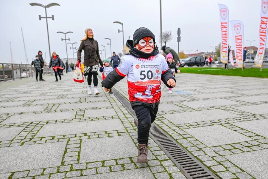 Bieg Polak Mały w Szczecinie. Dodatkowa pula 50 miejsc na 8. Szczeciński Bieg Niepodległości Chłopiec ubrany w biało-czerwoną koszulkę w czasie biegu.